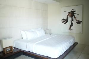 a bedroom with a white bed and a painting of a man at VILLA CELAVI 15 in Kerobokan +45 photos
