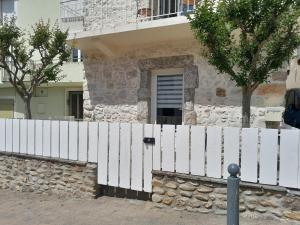 una cerca blanca frente a una casa en la placette en Hérépian