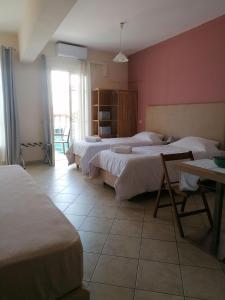 a bedroom with three beds and a table and a window at Ta Adelfia in Pylos