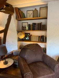 a living room with a brown leather couch and books at Fermette La bergerie in Cormont