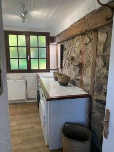 a kitchen with a counter and a stone wall at Fermette La bergerie in Cormont