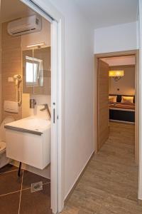 a bathroom with a white sink and a bedroom at Villa Mari Apartment in Medulin