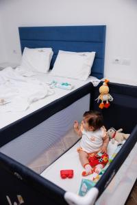 un bébé assis sur un lit avec des jouets dans l'établissement CAPTAIN'S RESIDENCE, à Ksamil