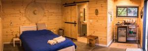 1 dormitorio con 1 cama en una cabaña de madera en אחוזת אבירי הגליל, en She'ar Yashuv