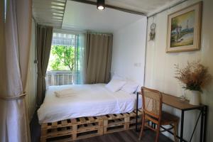 a bedroom with a bed and a desk and a window at Day Off House Chiang Mai Near Walking Street in Chiang Mai