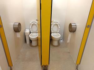 two toilets in a bathroom with yellow dividers at Boat Barcelona Yacht in Barcelona