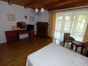 um quarto com uma cama, uma secretária e uma televisão em Lipowy Przylądek- Domek 12 