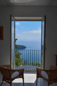 an open door to a balcony with a view of the ocean at IL GIARDINO SELVATICO DI SUCCELLARIO - APARTMENTS in Ischia