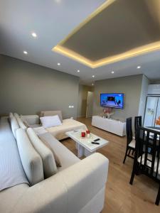 sala de estar con muebles blancos y TV de pantalla plana en Hotel Erioni, en Sarandë