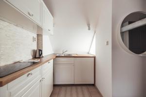 a kitchen with white cabinets and a sink and a mirror at Greatview Banensium Apartment in Banská Štiavnica