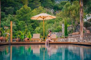 una mujer sentada junto a una piscina con sombrilla en The Remote Hotel en Sarigerme
