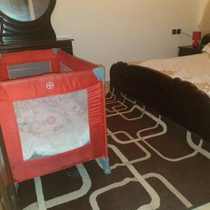 1 dormitorio con silla roja junto a la cama en Appartement Neuf pour location, en Martil