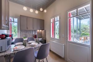 a kitchen with a table and chairs and windows at Sunset English Villas in Paralía