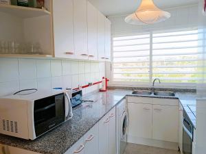 uma cozinha com armários brancos, um lavatório e um micro-ondas em Villa Service - Maricel M em El Vendrell