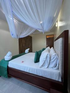 a bedroom with a large white bed with curtains at Nitro Homes Nyali in Mombasa