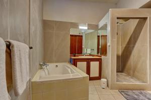 a bathroom with a tub and a shower and a sink at Vaste chambre vue mer montagne Ti Kaz Miyou 3 in La Possession