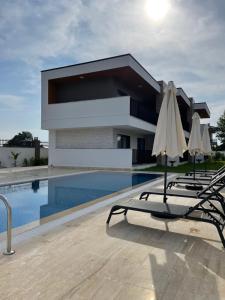 a house with a swimming pool with chairs and an umbrella at KALİDA APART in Kemer