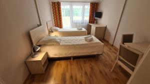 two beds in a small room with wooden floors at Zacisze Natura Tour in Spała