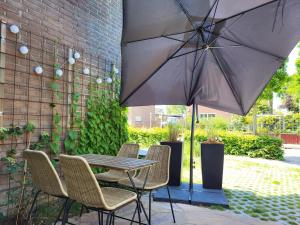 een tafel en stoelen met een parasol op een patio bij Het Huisje comfortabel, luxe & sfeervol nabij het strand in Biggekerke