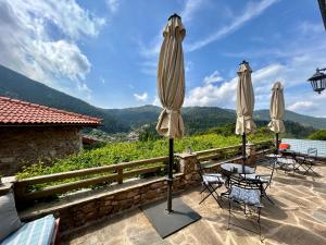 eine Terrasse mit 2 Sonnenschirmen, einem Tisch und Stühlen in der Unterkunft Pritanio in Polídhroson