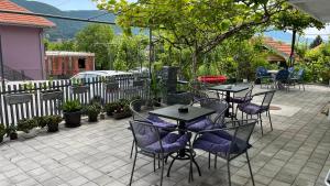 eine Terrasse mit Tischen, Stühlen und einem Zaun in der Unterkunft Apartmani Kalea in Sokobanja