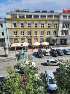 a large yellow building with cars parked in a parking lot at Apartament z widokiem na Rynek Kościuszki in Białystok