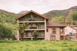 una vecchia casa con montagne sullo sfondo di Apartamentos El Valle ad Avín