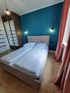 a large bed in a room with a blue wall at Apartament z widokiem na Rynek Kościuszki in Białystok