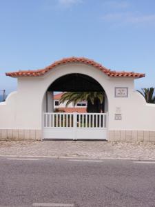 a white building with a gate and a fence at Alto da Praia Villa in Colares