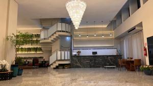 a lobby with a chandelier and a staircase in a building at Hotel Dan Inn Uberlandia in Uberlândia