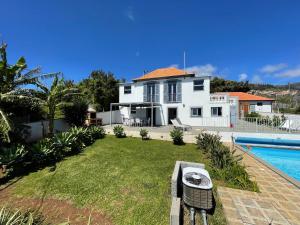 a white house with a swimming pool next to a yard at Tranquilidade in Estreito da Calheta +21 photos