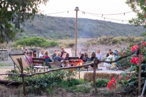 un groupe de personnes assises sur des bancs dans un jardin dans l'établissement Soul Farm Algarve - Glamping & Farm Houses, à Aljezur