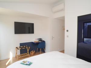 1 dormitorio con 1 cama, escritorio y TV en Hôtel Les Mouettes en La Couarde-sur-Mer