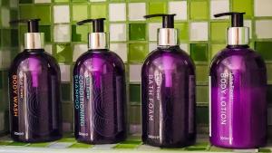 four purple shampoo bottles sitting on a shelf at Centara Muscat Hotel Oman in Muscat