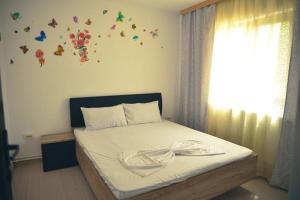una camera da letto con un letto con lenzuola bianche e farfalle sul muro di Casa Rebeka a Năvodari