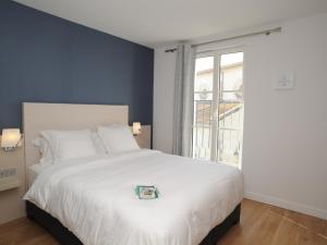 - une chambre avec un grand lit blanc et une fenêtre dans l'établissement Hôtel Les Mouettes, à La Couarde-sur-Mer