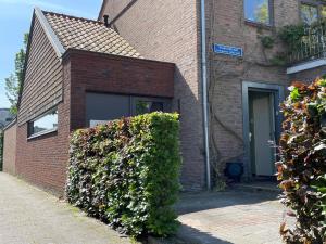 a brick building with a window and a bush at Huisje Vivaldi in Den Bosch