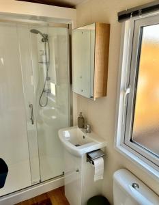 a white bathroom with a shower and a sink at Traumlage Meerblick Nr 26 Ferienhaus "Schau aufs Meer" erste Reihe unendliche Weite, eingebettet in der Natur in Westerland