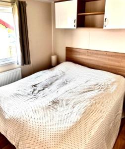 a bedroom with a bed with a wooden headboard and a window at Traumlage Meerblick Nr 26 Ferienhaus "Schau aufs Meer" erste Reihe unendliche Weite, eingebettet in der Natur in Westerland