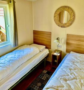 two beds in a room with a mirror on the wall at Traumlage Meerblick Nr 26 Ferienhaus "Schau aufs Meer" erste Reihe unendliche Weite, eingebettet in der Natur in Westerland