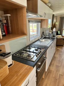 a kitchen with a stove and a sink in it at Traumlage Meerblick Nr 26 Ferienhaus "Schau aufs Meer" erste Reihe unendliche Weite, eingebettet in der Natur in Westerland