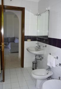 a bathroom with a sink and a toilet and a mirror at IL GIARDINO SELVATICO DI SUCCELLARIO - APARTMENTS in Ischia