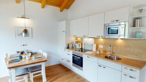 une cuisine avec des placards blancs et un comptoir en bois dans l'établissement Feriendorf Südstrand Haus 36, à Pelzerhaken