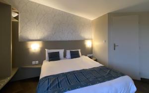 a bedroom with a large bed with blue and white sheets at Charme Hôtel et Spa, Montbéliard Sud in Montbéliard