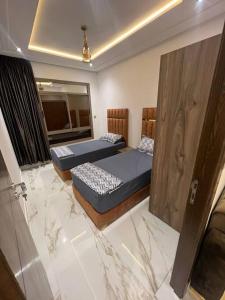 2 Betten in einem Zimmer mit Marmorböden in der Unterkunft appartement de luxe hay almatar 3 in Nador