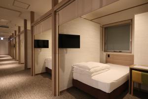 a hotel room with two beds and a window at Cabin & Capsule Hotel J-SHIP Osaka Namba in Osaka