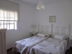 1 dormitorio con 2 camas en una habitación blanca en El Magnolio, en Chiclana de la Frontera