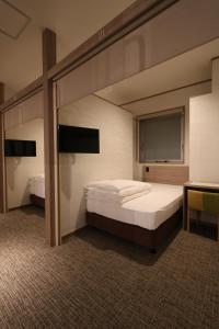 a bedroom with two bunk beds and a flat screen tv at Cabin & Capsule Hotel J-SHIP Osaka Namba in Osaka