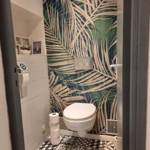 a bathroom with a toilet and a tropical wallpaper at Gîte Saint Sauveur in Brévilly +19 photos