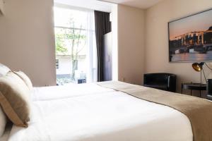 Un dormitorio con una gran cama blanca y una ventana en Frankendael Apartments, en Ámsterdam